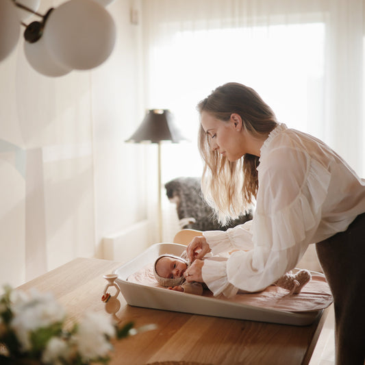 mom getting a baby dressed on changing pad