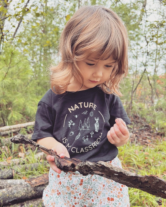 little toddler girl playing in nature outdoors nature classroom exploring