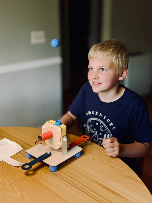 Child at a table with a completed CrunchLabs Air Ball build, a blue foam ball hovering above the machine