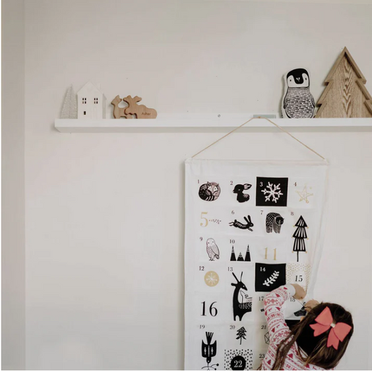 a young girl checking her eco-friendly organic cotton christmas advent calendar by wee gallery