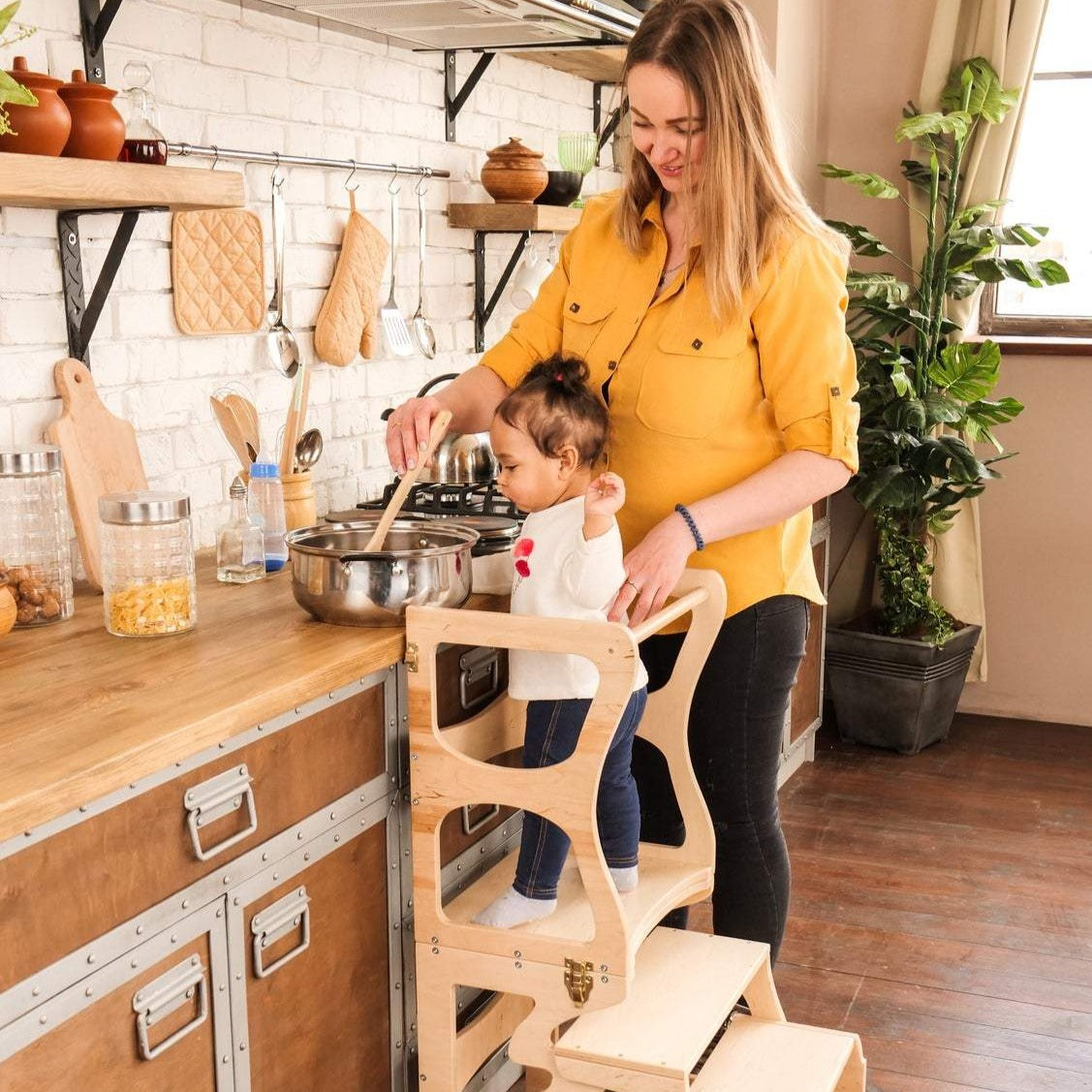 mom and daughter cooking together in the kitchen little girl using eco-friendly wooden convertible kitchen tower step stool