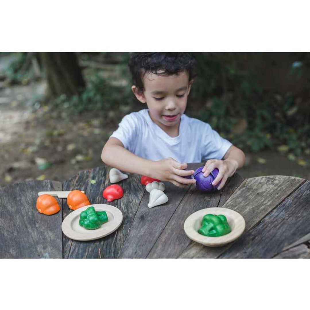 little boy playing with eco-friendly non-toxic wooden pretend play veggie set outside by plantoys