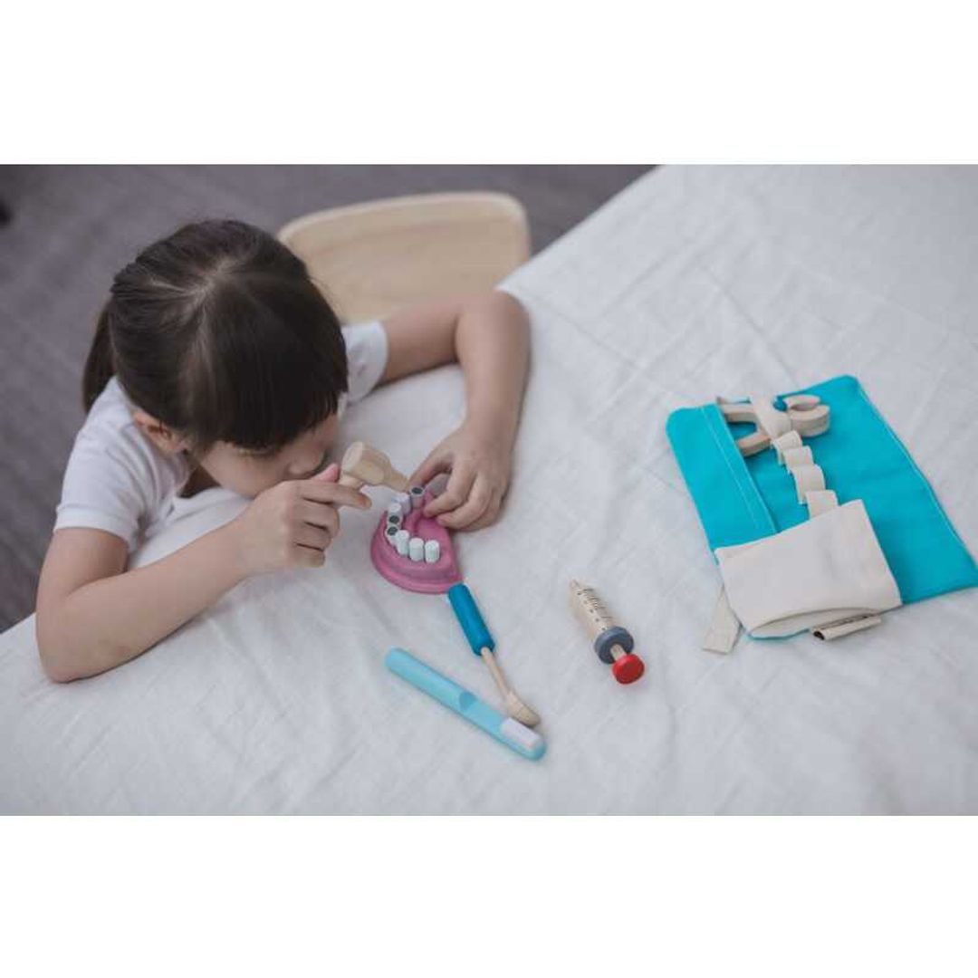 little girl playing with eco-friendly wooden dentist pretend play set by plantoys