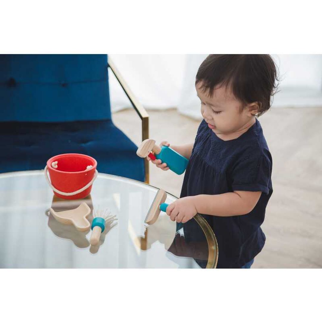 little boy playing pretend with eco-friendly cleaning set by plantoys