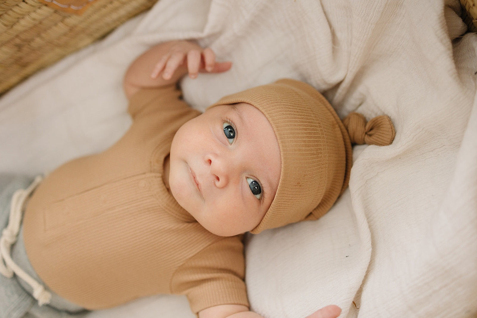 baby in bassinet wearing organic cotton knot hat and onesie mebie baby