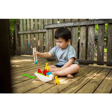 Load image into Gallery viewer, little boy sitting on the deck playing with plantoys wooden eco-friendly balancing boat toy
