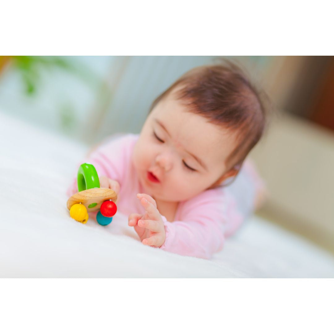 baby playing with non-toxic eco-friendly wooden sensory rattle  by plantoys