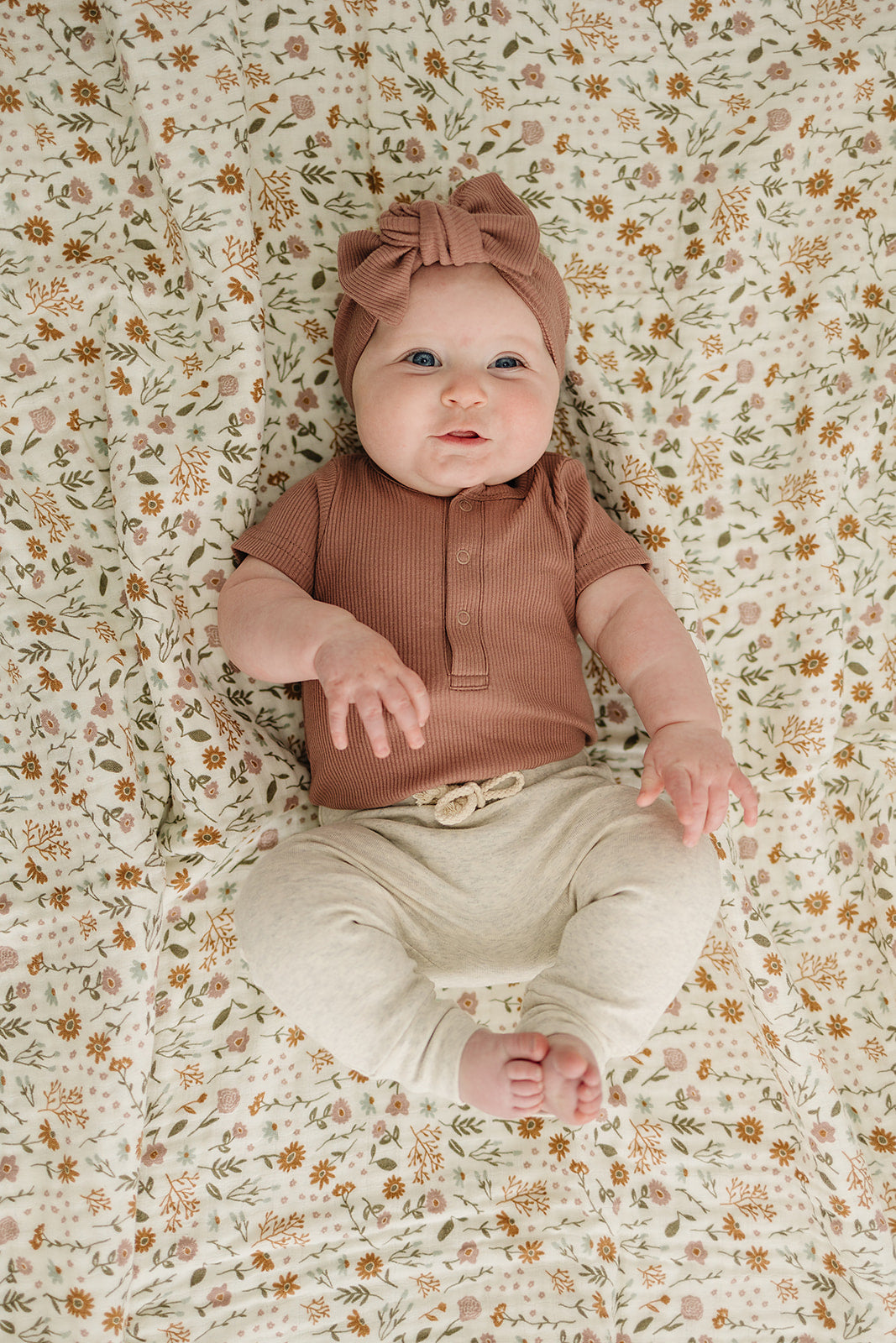baby girl smiling wearing organic cotton short sleeve onesie and matching bow head wrap