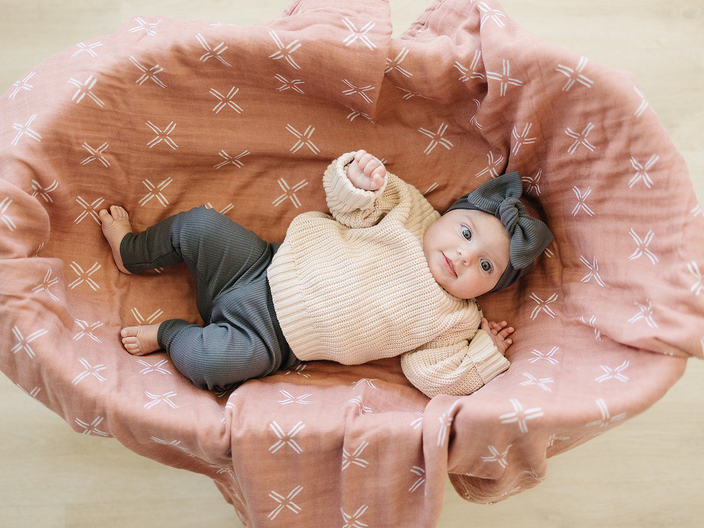 baby girl in bassinet wearing organic cotton knit pants and bow headband