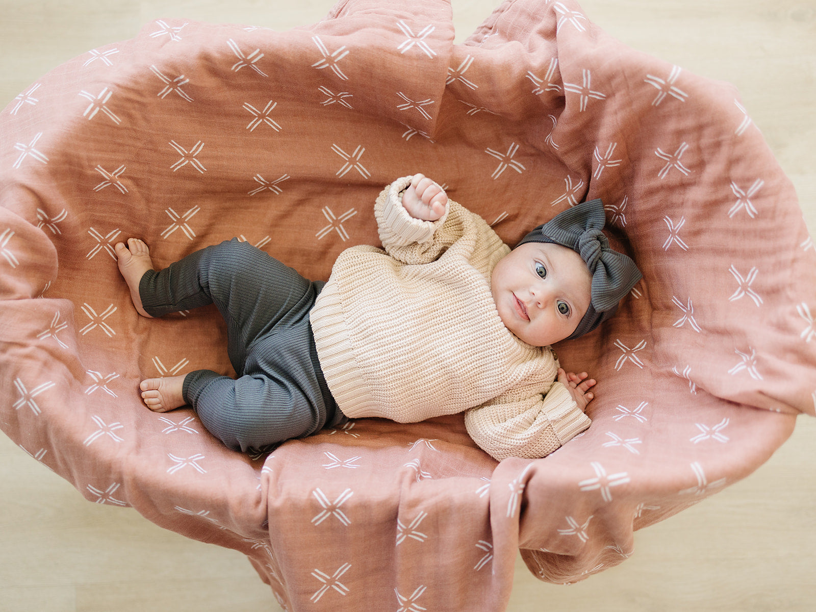 baby girl in bassinet wearing organic cotton knit pants and bow headband