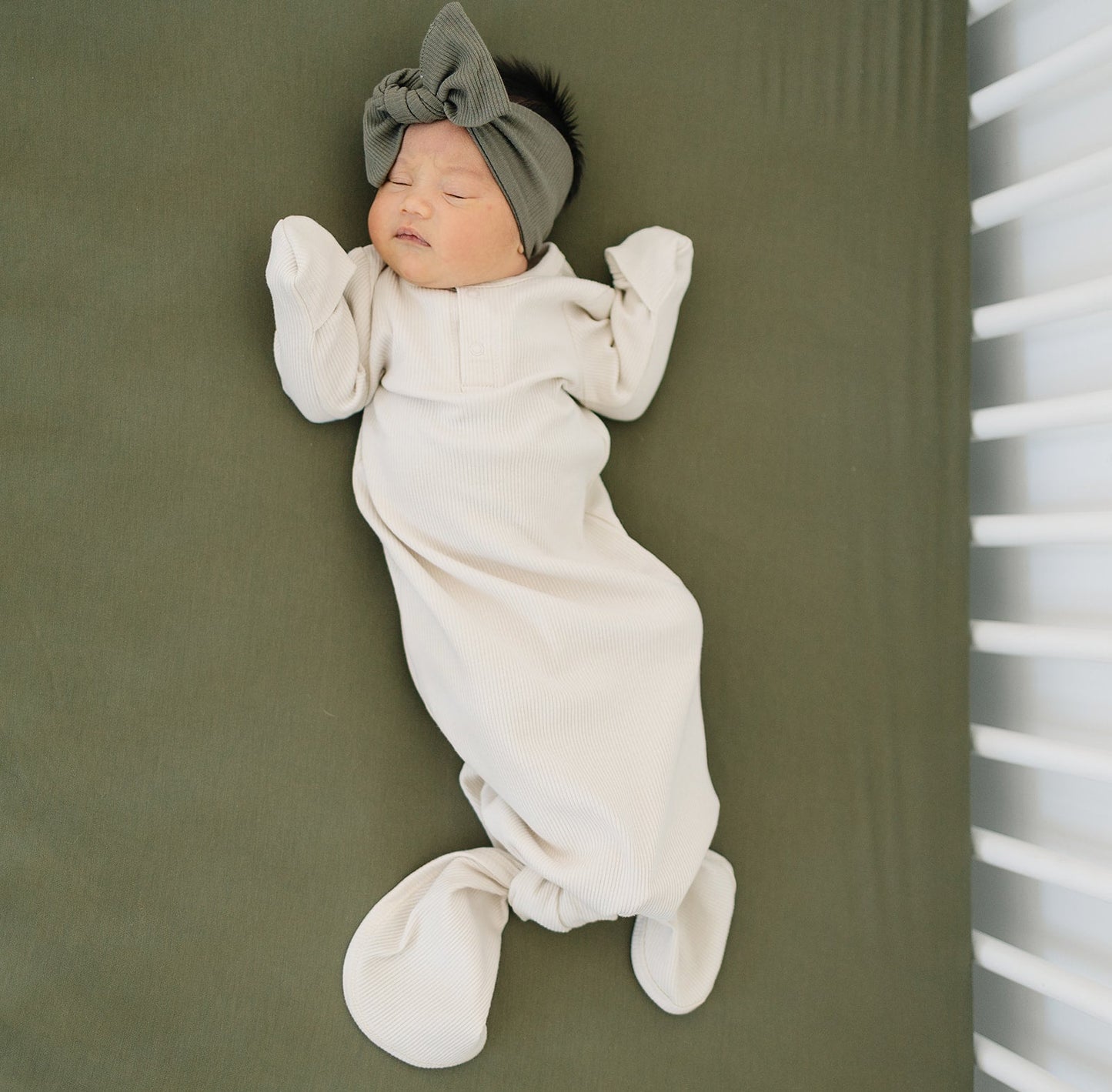 baby girl sleeping in a crib wearing organic cotton baby knot gown and bow head wrap mebie baby non-toxic eco-friendly