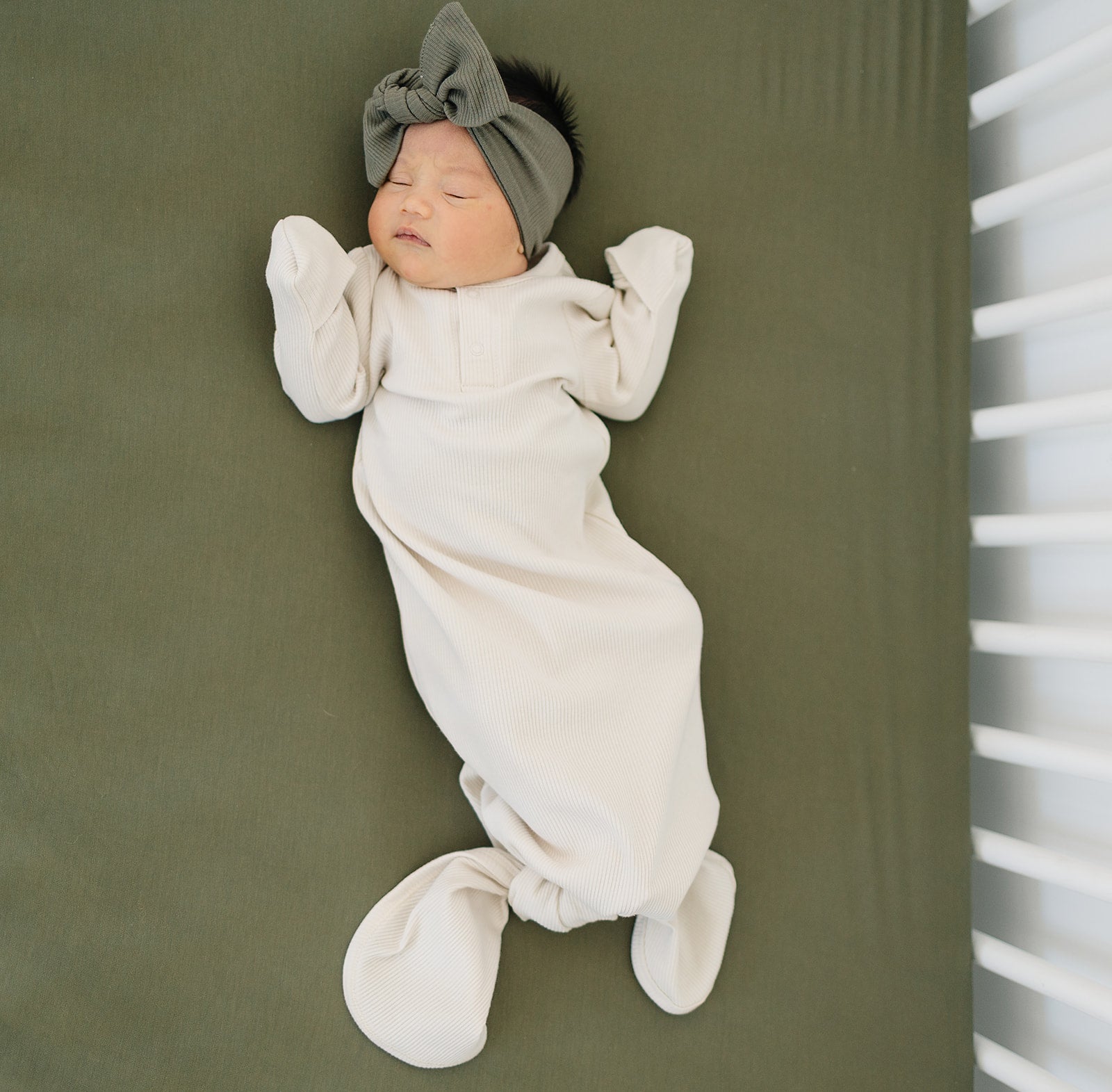 baby girl sleeping in a crib wearing organic cotton baby knot gown and bow head wrap mebie baby non-toxic eco-friendly