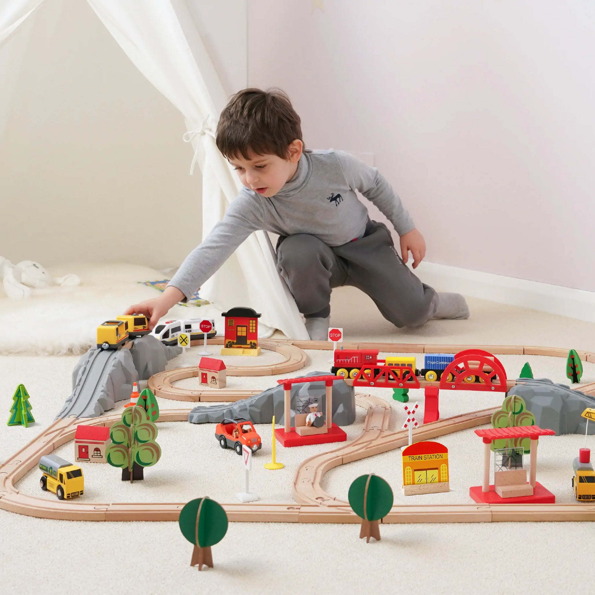 a boy playing with wooden eco-friendly train track set by tiny land