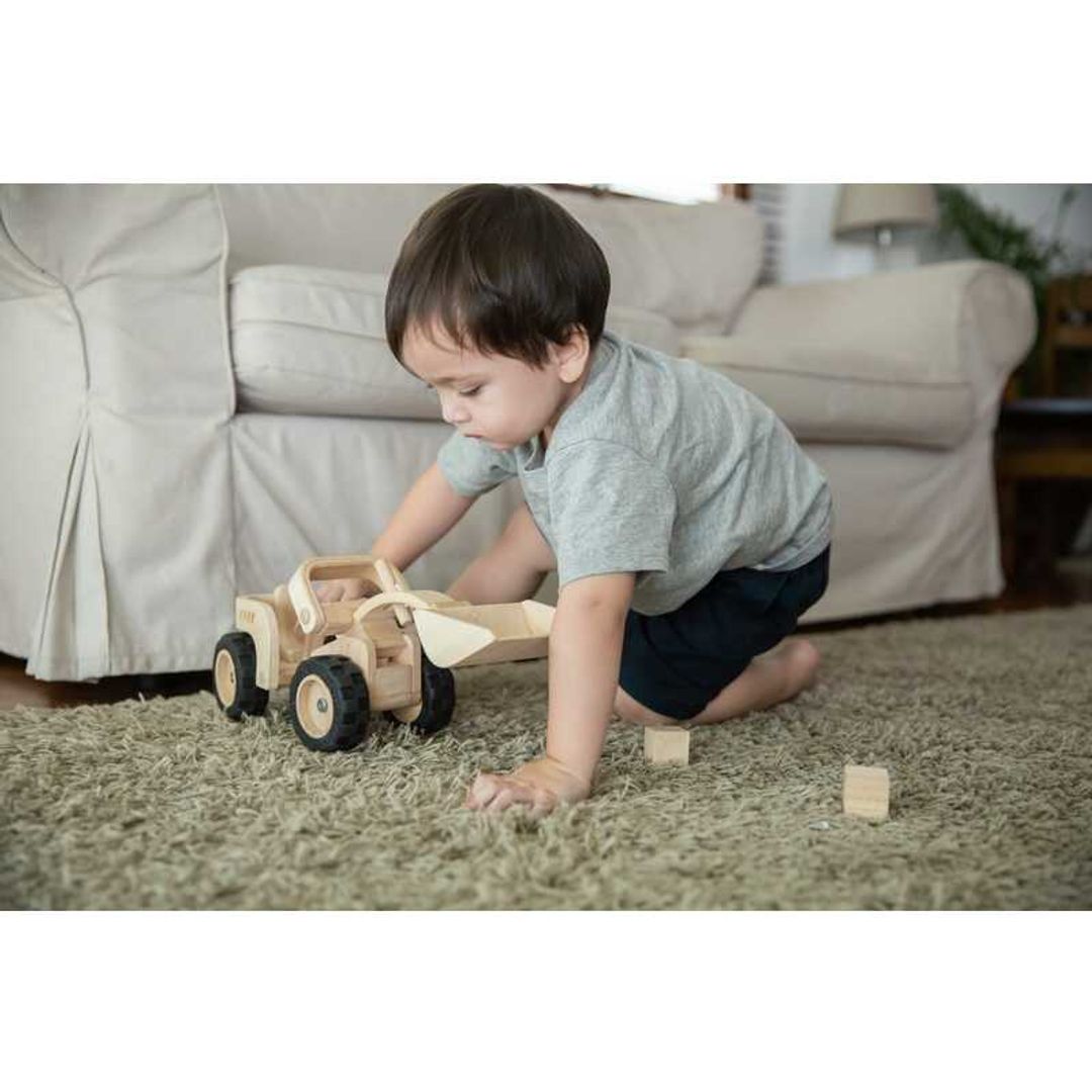 little boy playing on the floor with a wooden eco-friendly non-toxic bulldozer by plantoys