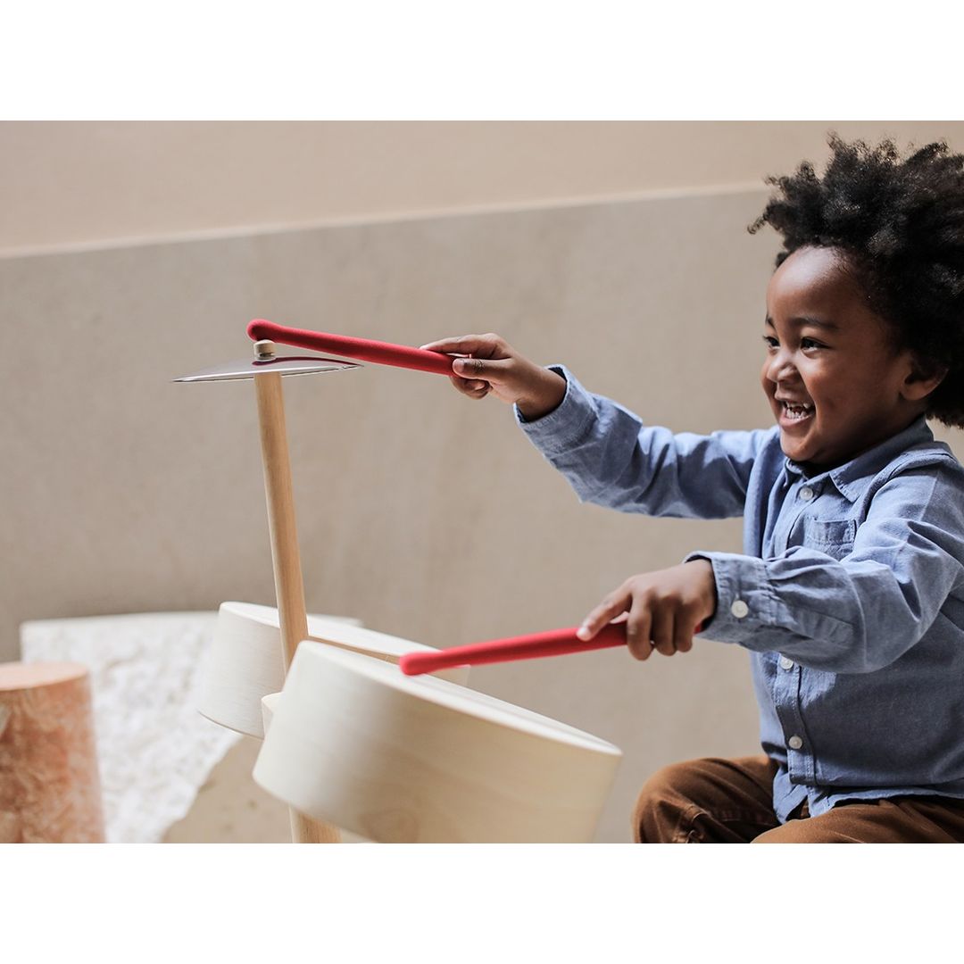 little boy playing eco-friendly non-toxic wooden drums by plantoys