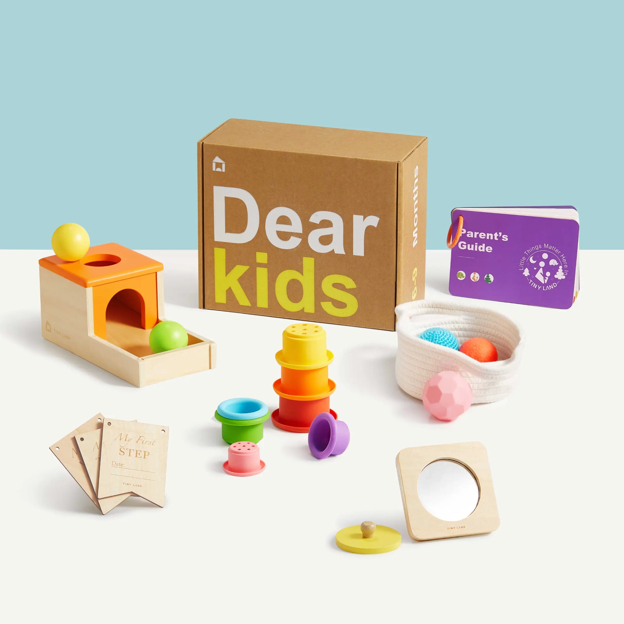 A wooden Montessori toy set from Tiny Land including an object permanence box and a sensory ball.