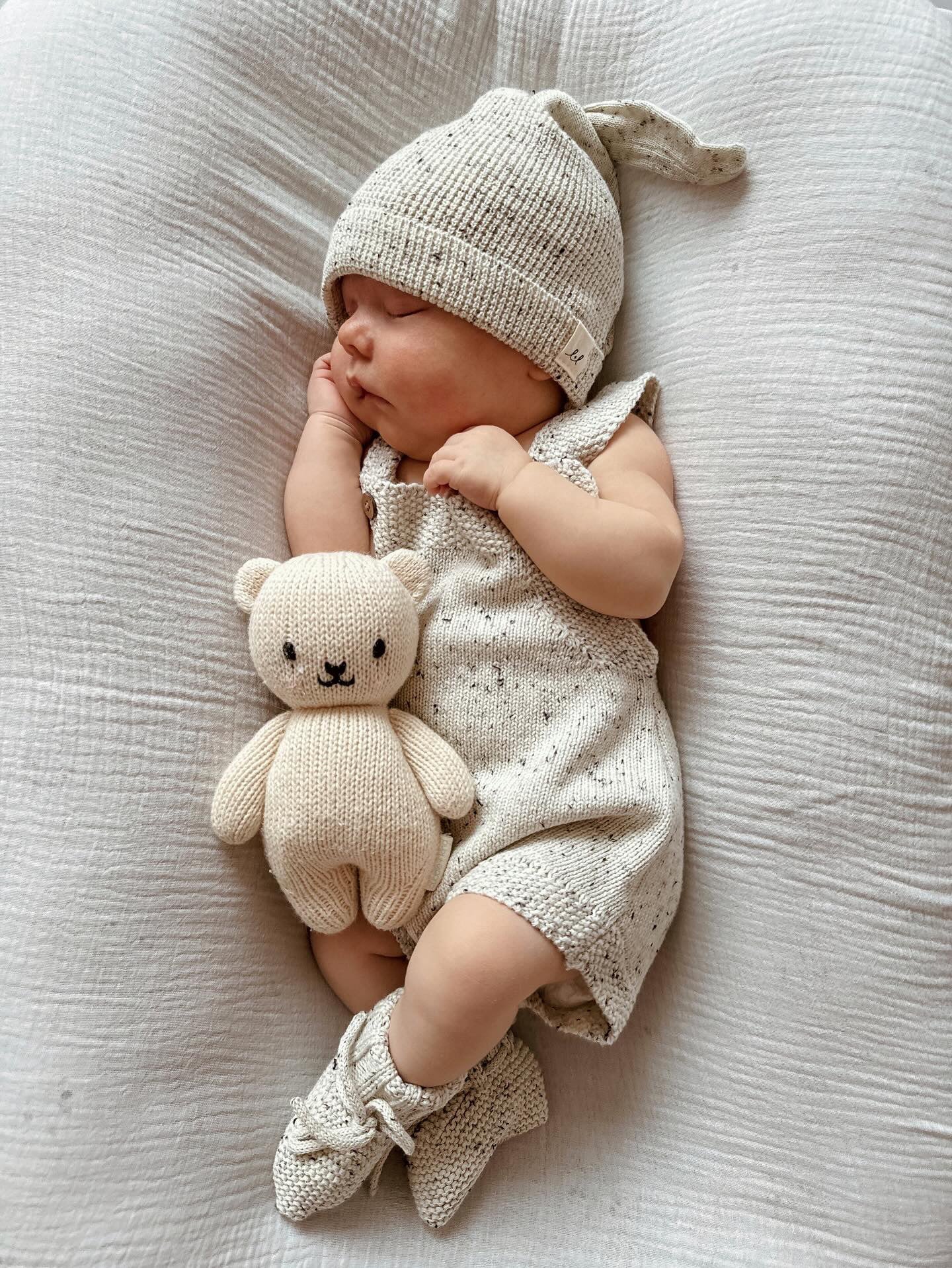 baby sleeping wearing organic cotton knit romper booties and organic cotton knot hat