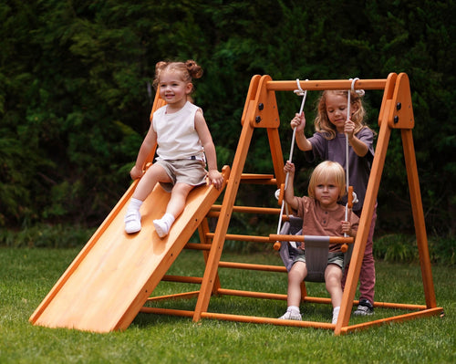 3 kids playing outside on eco-friendly wooden cedar foldable outdoor indoor playset with slide ladder and swing by avenlur