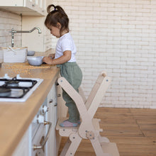 Load image into Gallery viewer, little girl helping in the kitchen on eco-friendly non-toxic wooden foldable montessori kitchen tower step stool 
