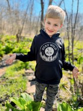 Load image into Gallery viewer, A child outdoors in nature wearing organic nature-inspired hoodie with slogan &quot;stay wild&quot; 
