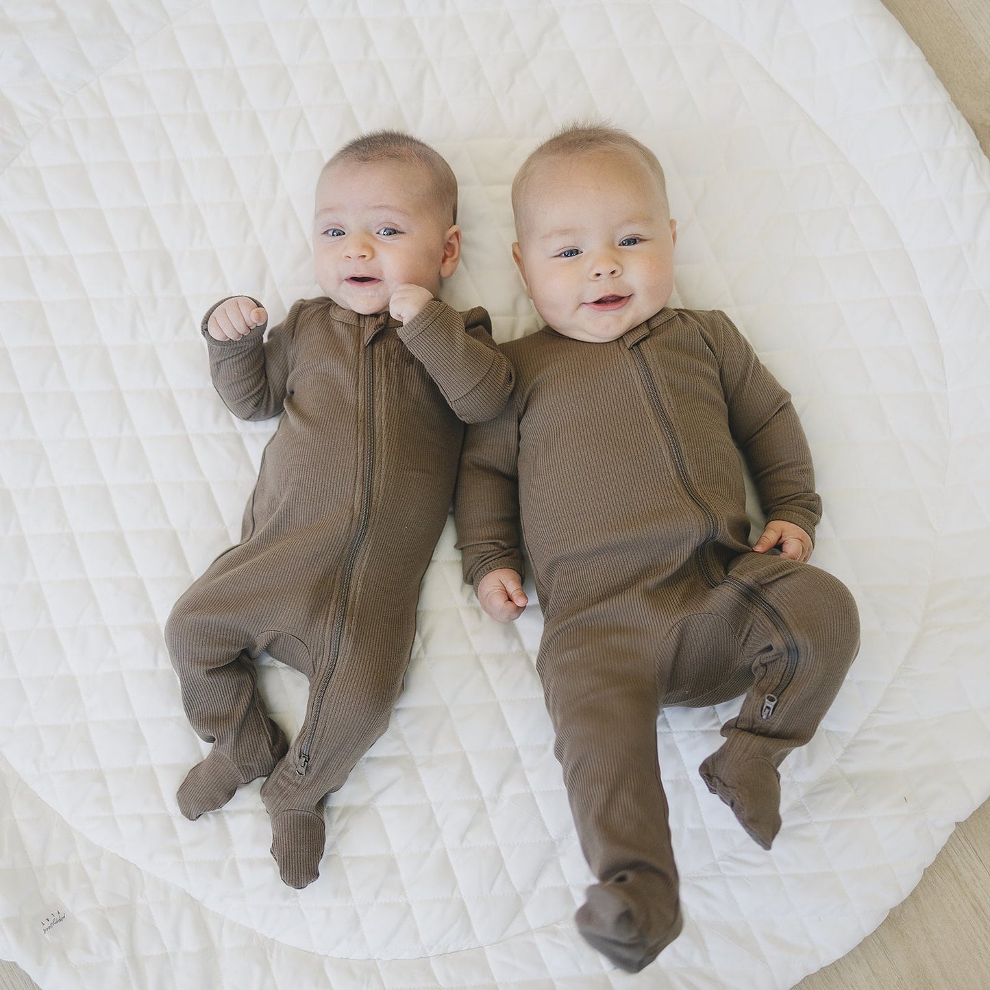 two babies laying down wearing cocoa color organic cotton ribbed zipper footed pajamas by mebie baby