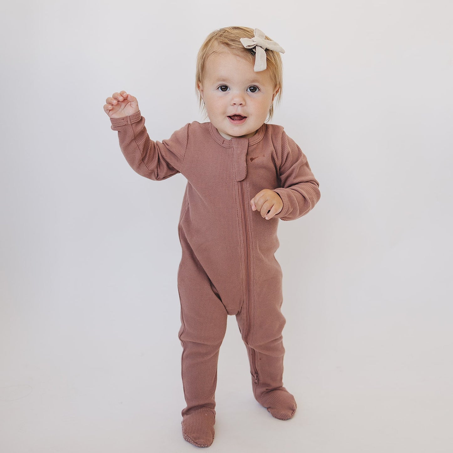 baby girl wearing organic cotton ribbed footed onesie pajamas by mebie baby and bow tie in hair