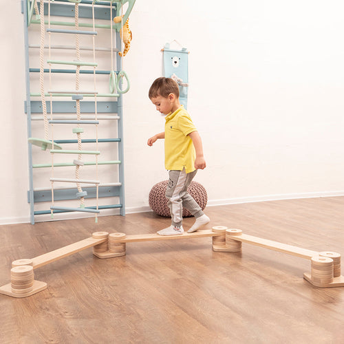 toddler boy walking on eco-friendly wooden balance beam by wood and hearts