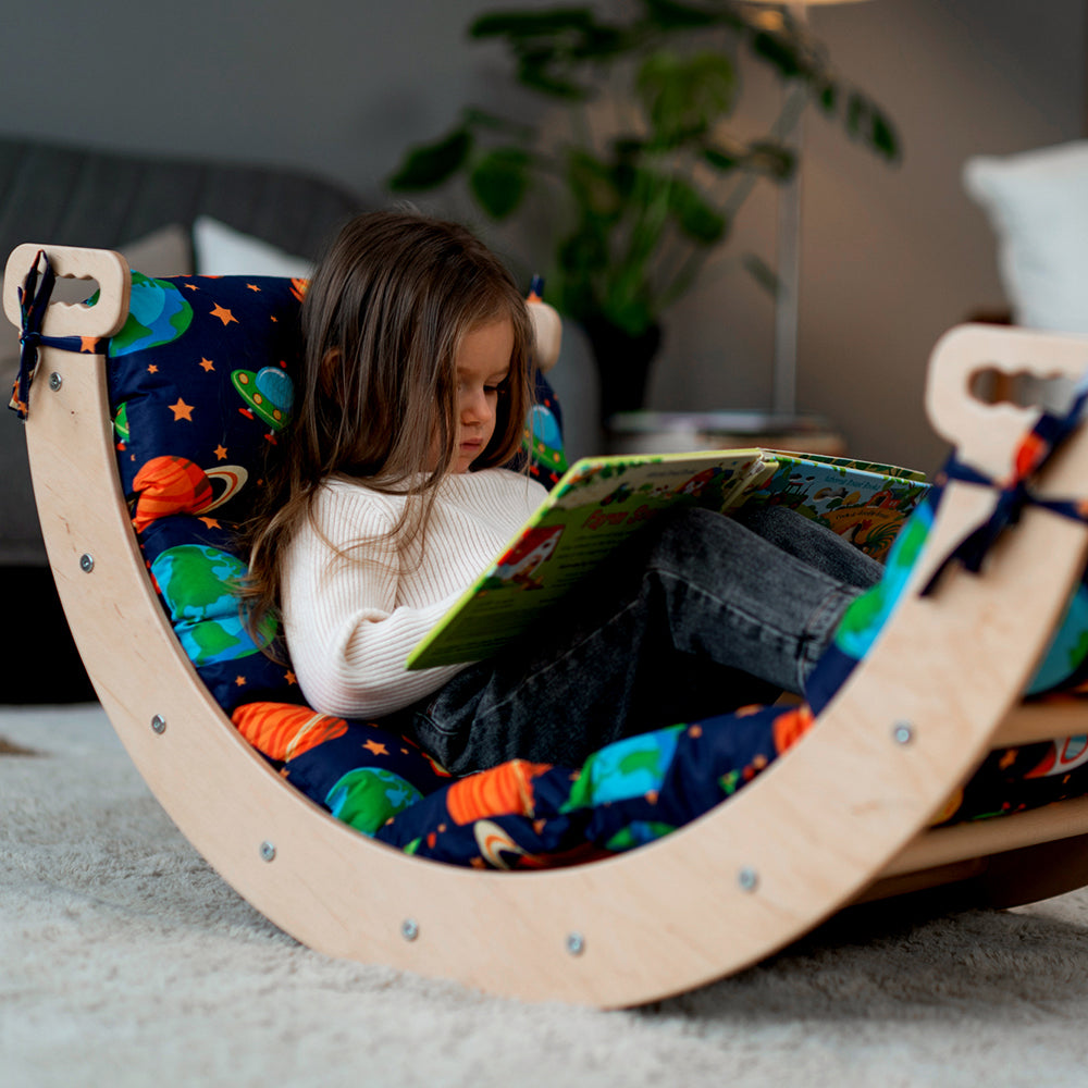 little girl reading on wooden eco-friendly arch with cushion by wood and hearts