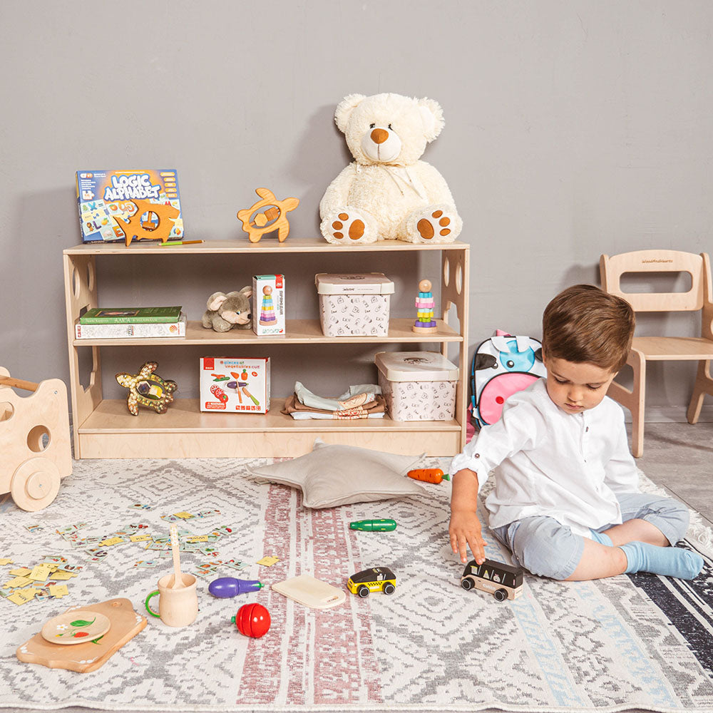 little boy playing in play room with eco-friendly non-toxic montessori shelf with toys in the background