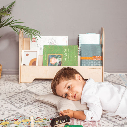 little boy in playroom in front of eco-friendly non-toxic wooden montessori book shelf by wood and hearts