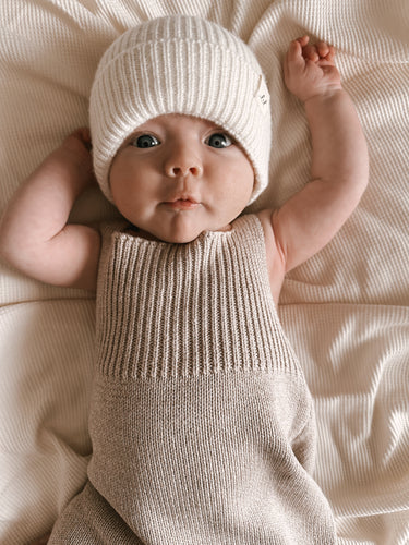 baby laying wearing organic cotton ribbed knit romper and merino wool  knit beanie hat