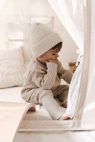 toddler sitting wearing organic cotton ribbed knit beige leggings and pullover 