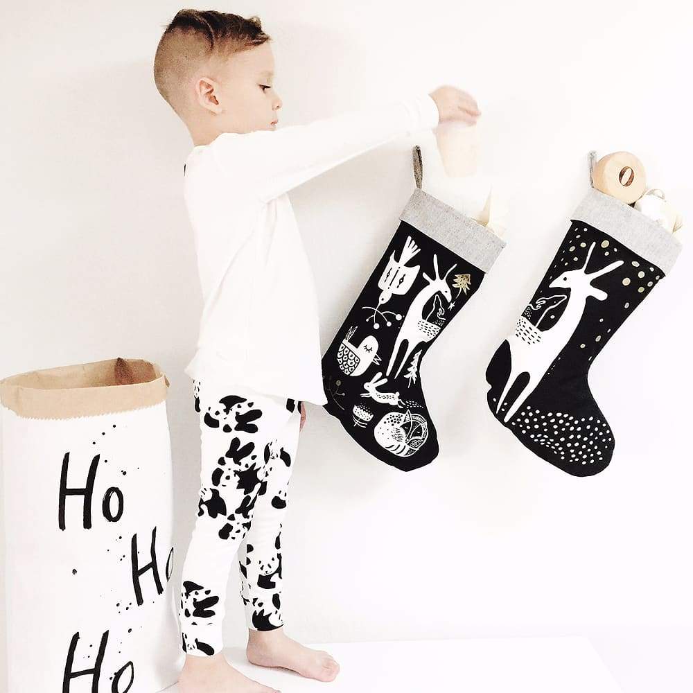 little boy checking organic cotton eco-friendly non-toxic christmas stocking in black and white minimalist nature-inspired deer design by wee gallery