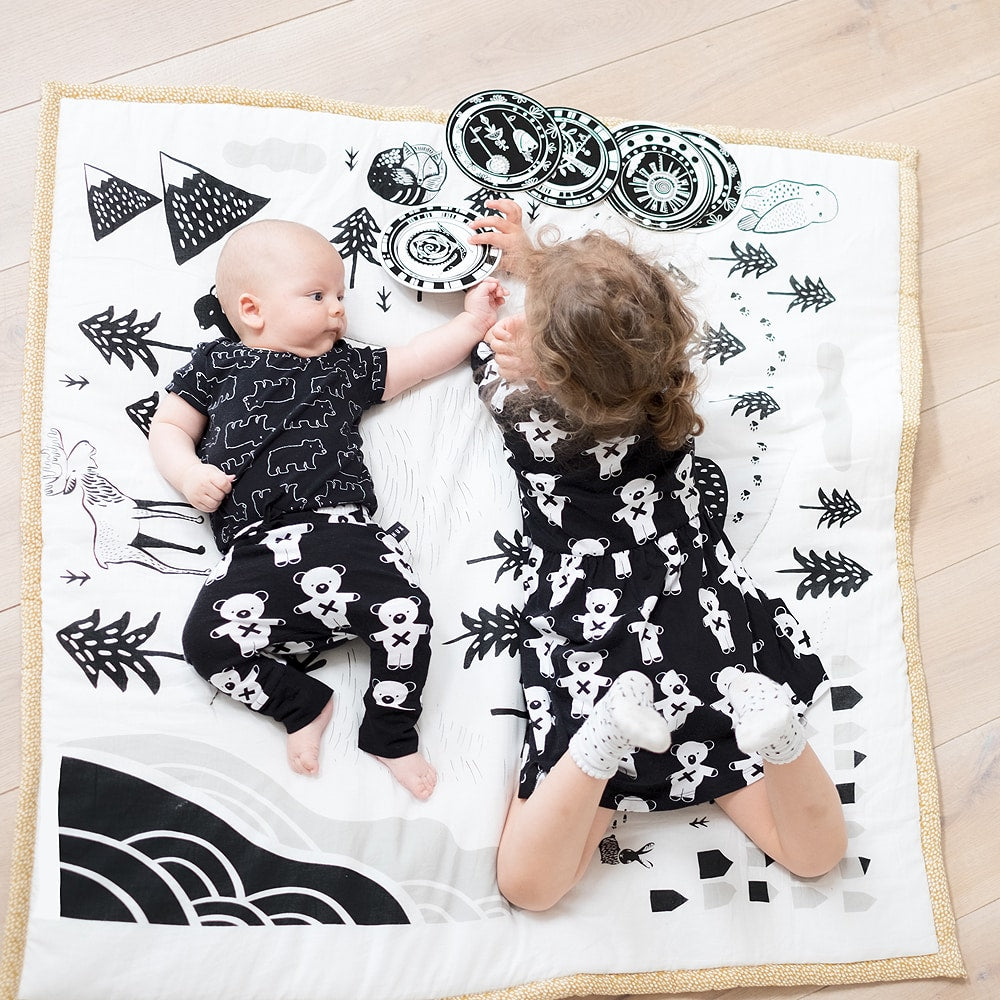 little girl playing with baby on organic cotton playmat by wee gallery