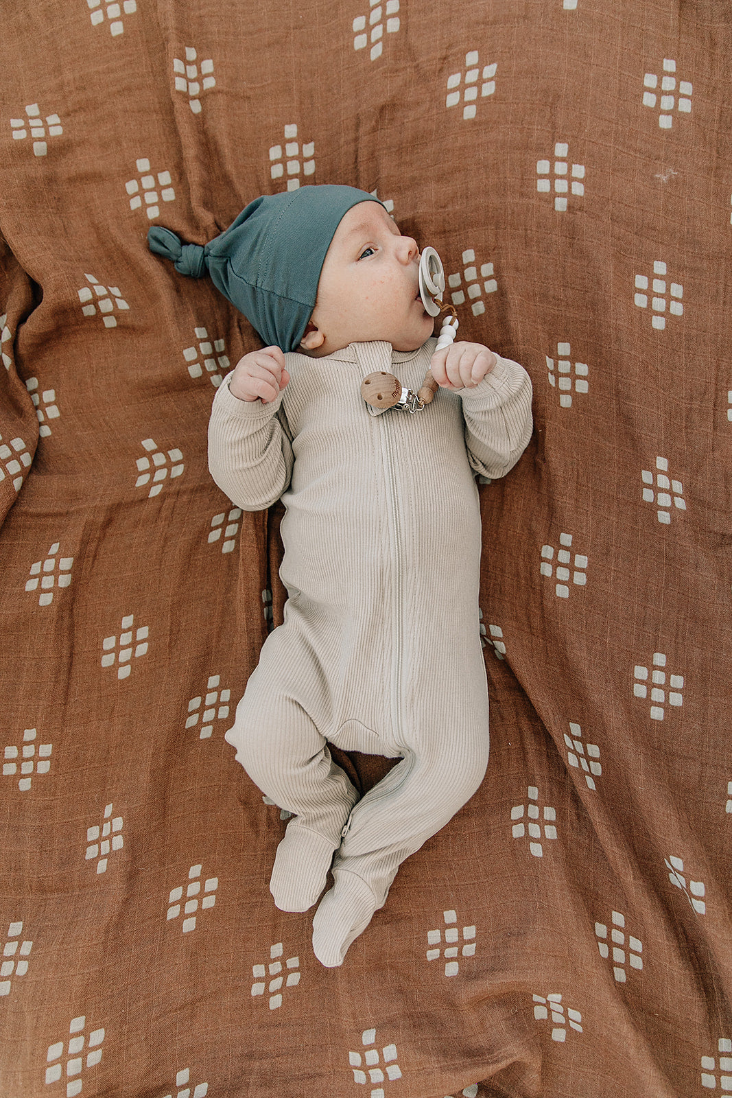 baby with pacifier wearing organic cotton oatmeal color zipper footed pajamas with knot hat by mebie baby