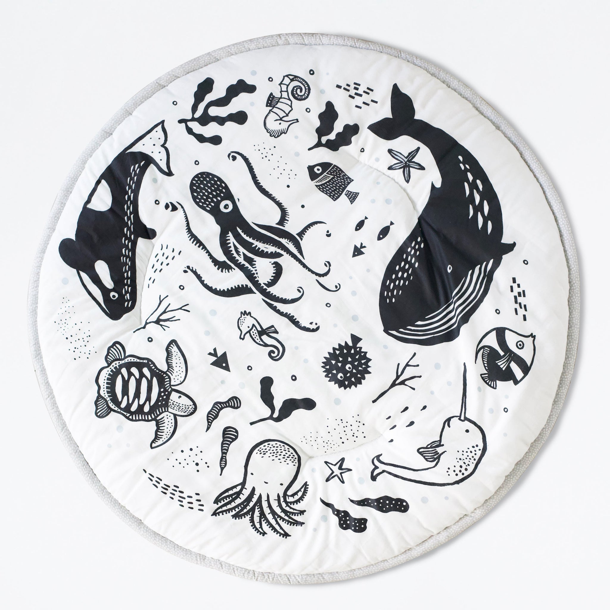 A baby doing tummy time on the high-contrast black and white Wee Gallery Ocean Playmat made of organic cotton.