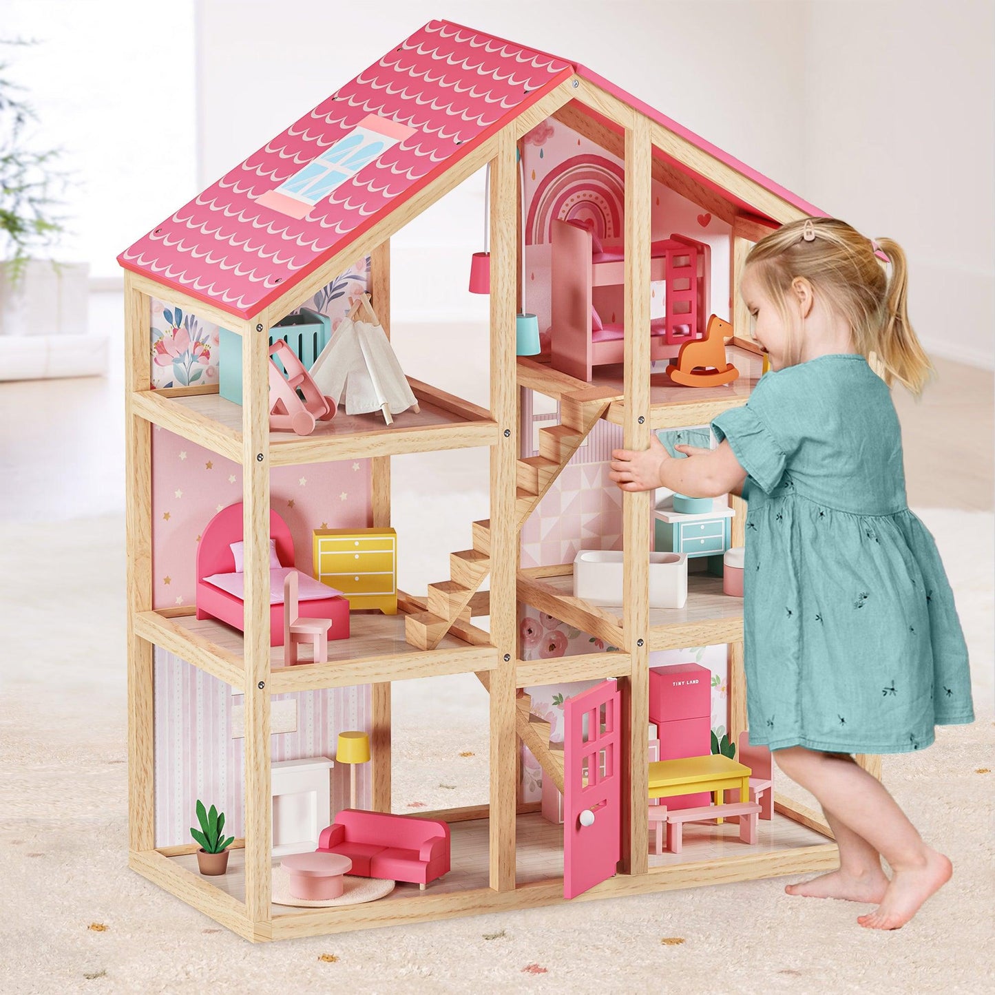 little girl playing with wooden sustainable doll house with furniture by tiny land