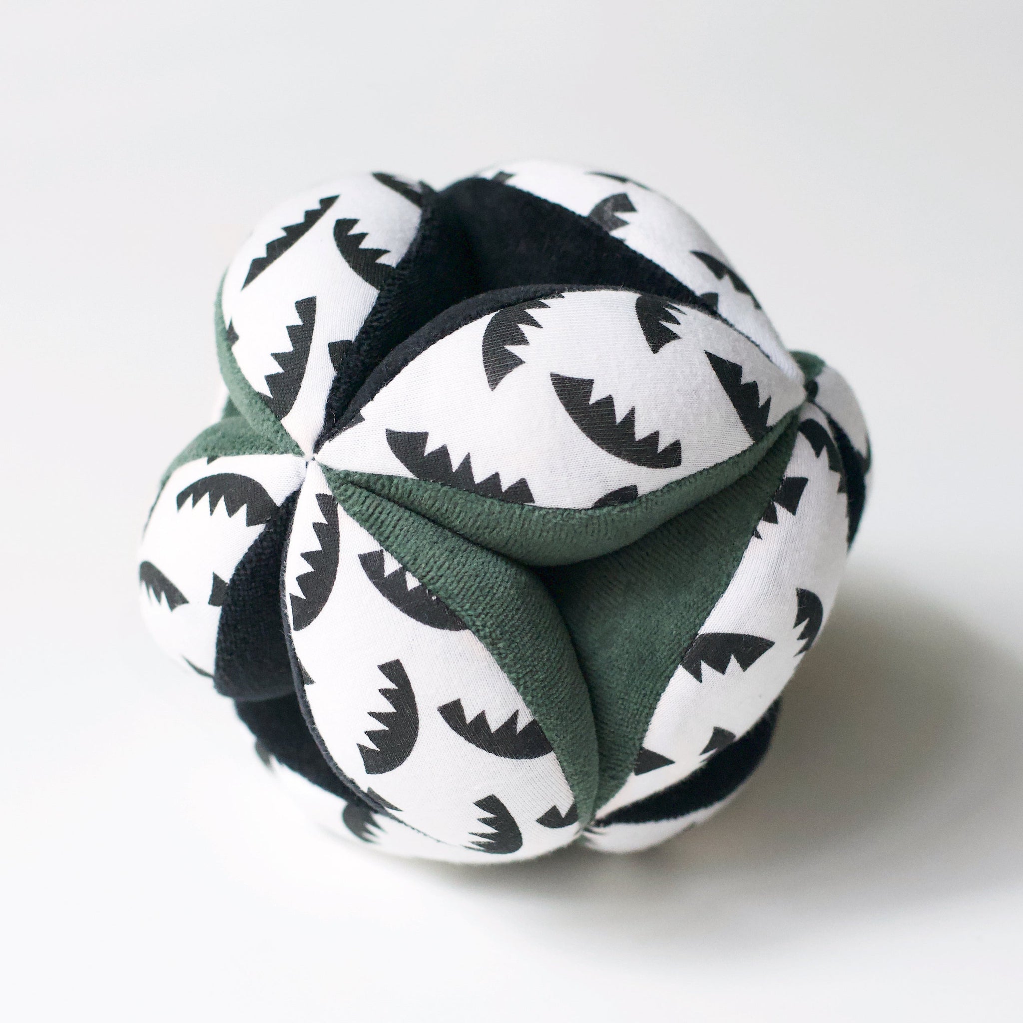 A soft organic cotton sensory clutch ball with jungle leaf patterns, perfect for a baby's grip.